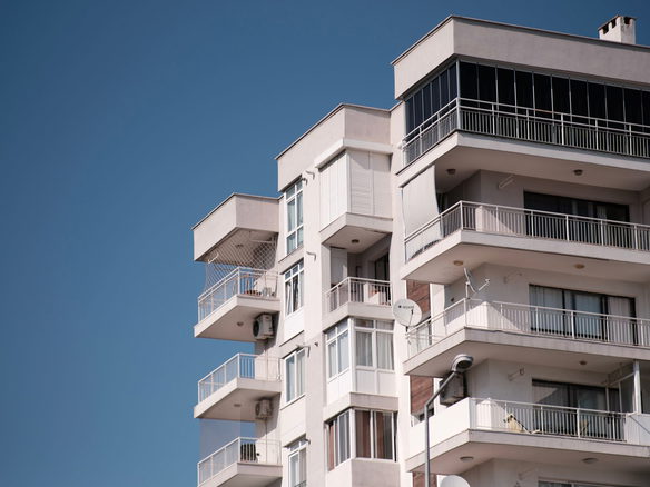 Contemporary apartment building in İzmir under clear blue sky, showcasing modern architecture.