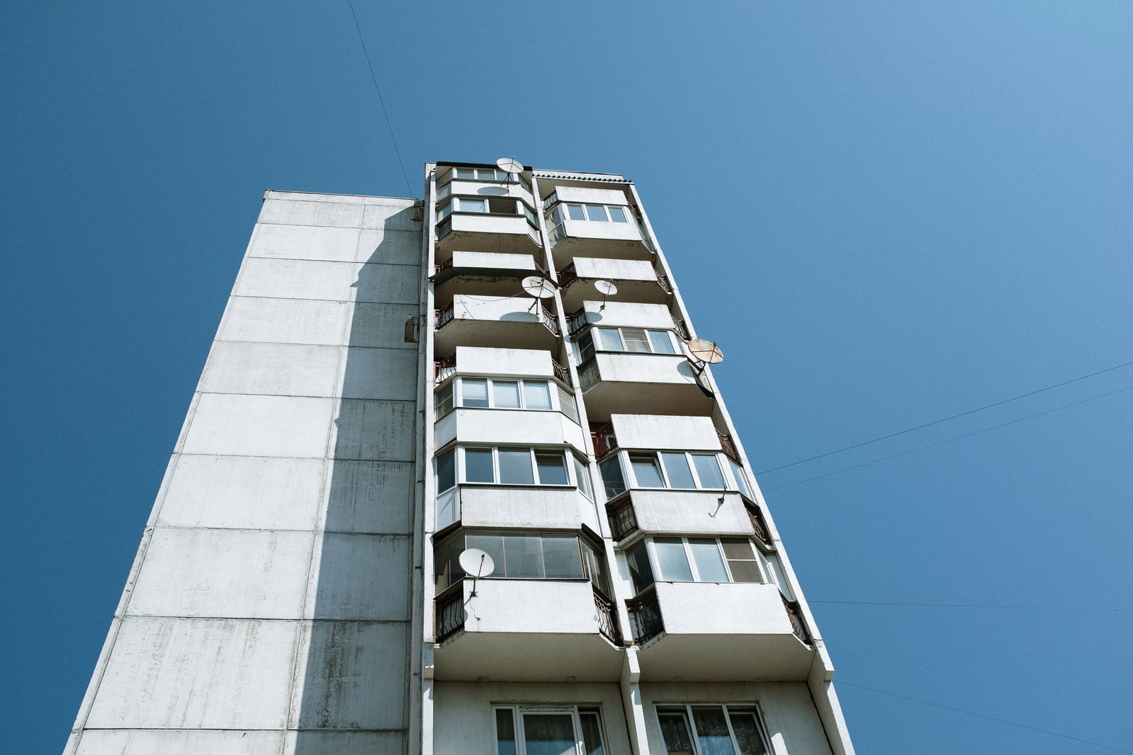 Low angle view of Soviet-style panel apartment building with blue sky backdrop.