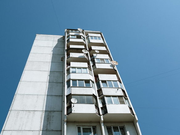 Low angle view of Soviet-style panel apartment building with blue sky backdrop.