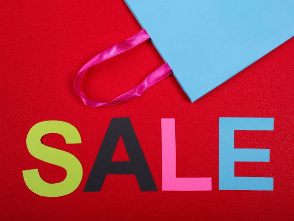 Vibrant shopping sale design with colorful letters and blue bag against a red backdrop.