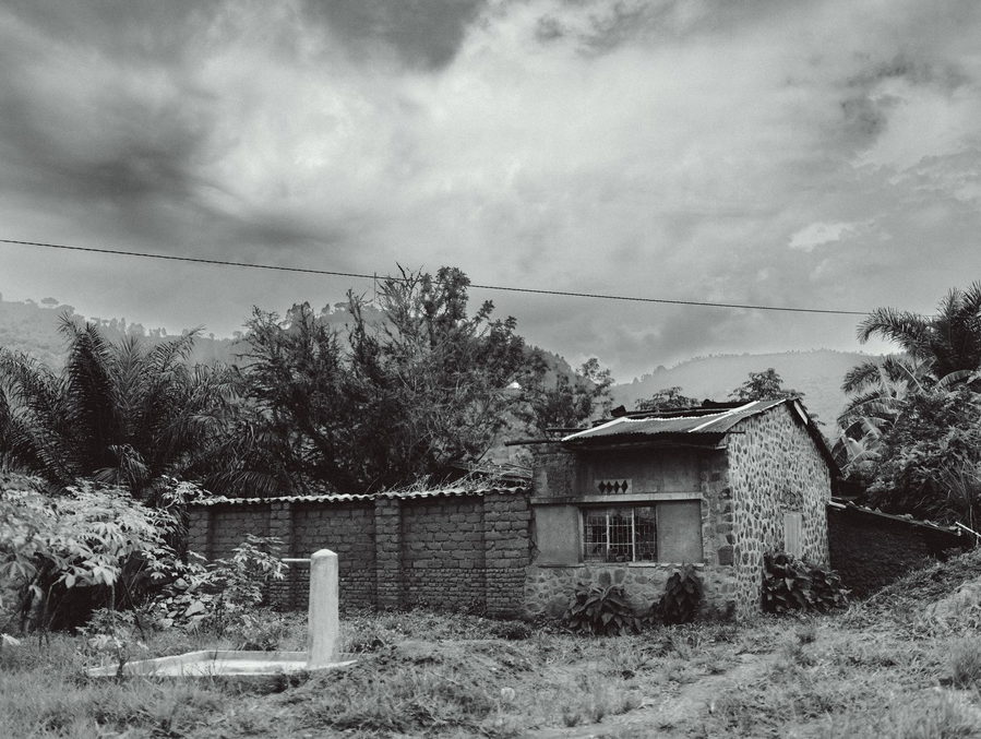 Black and white image of a rural stone house surrounded by lush foliage in Bujumbura, Burundi.