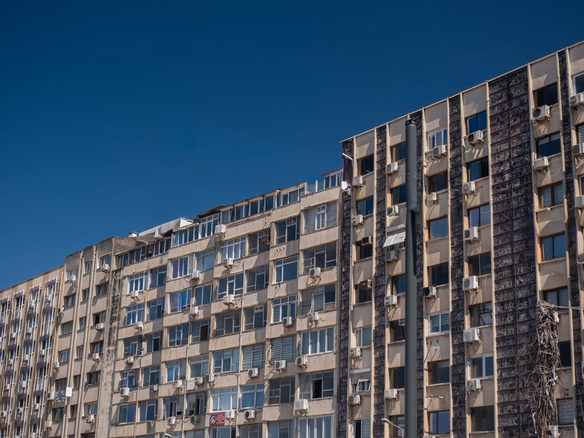 High-rise residential building with air conditioners in İzmir, Türkiye under a clear blue sky.
