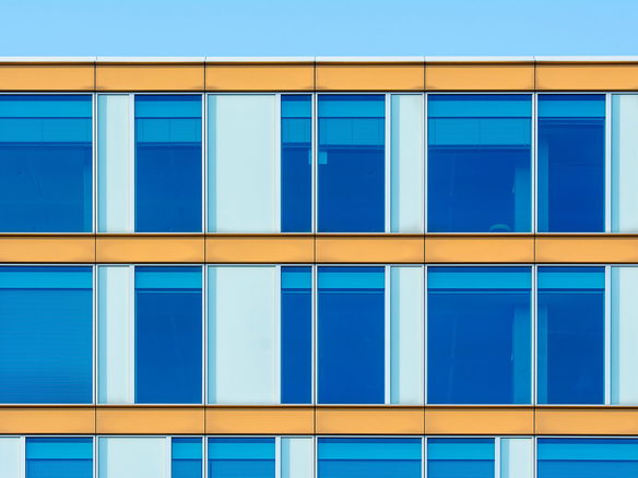 Contemporary office building facade showcasing blue windows and yellow structure.