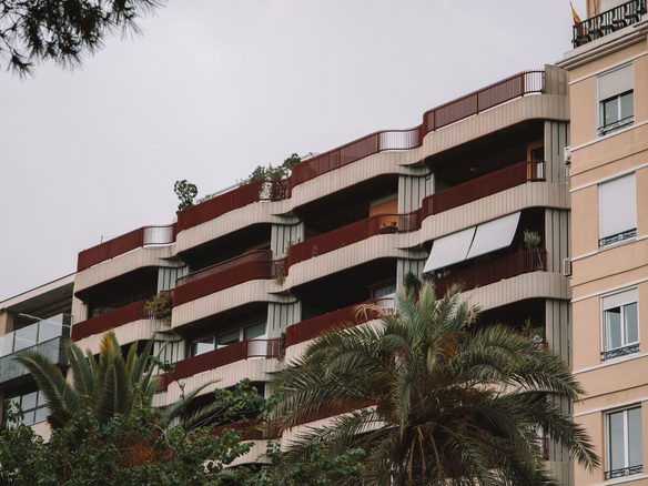 A detailed view of modern apartment architecture in Valencia, Spain with palm trees framing the scene.