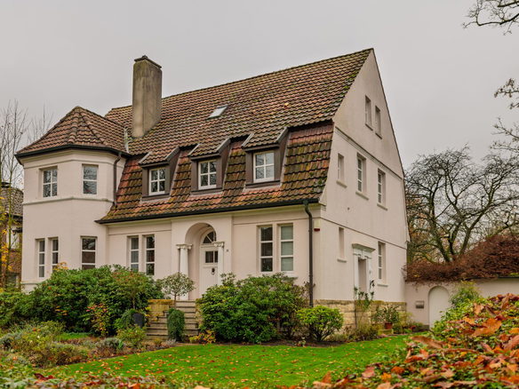 Elegant Tudor style house surrounded by autumn foliage, evoking a warm and cozy atmosphere.