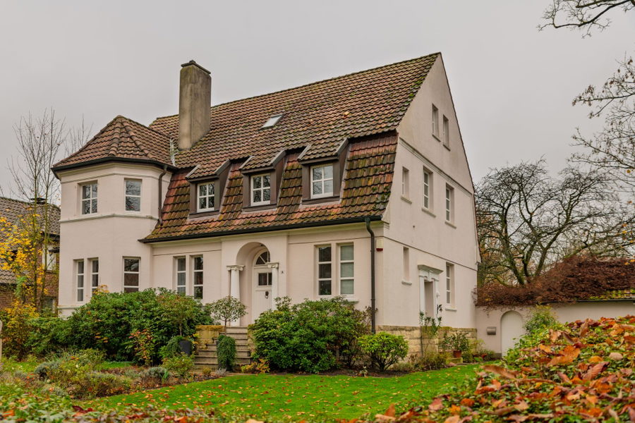 Elegant Tudor style house surrounded by autumn foliage, evoking a warm and cozy atmosphere.