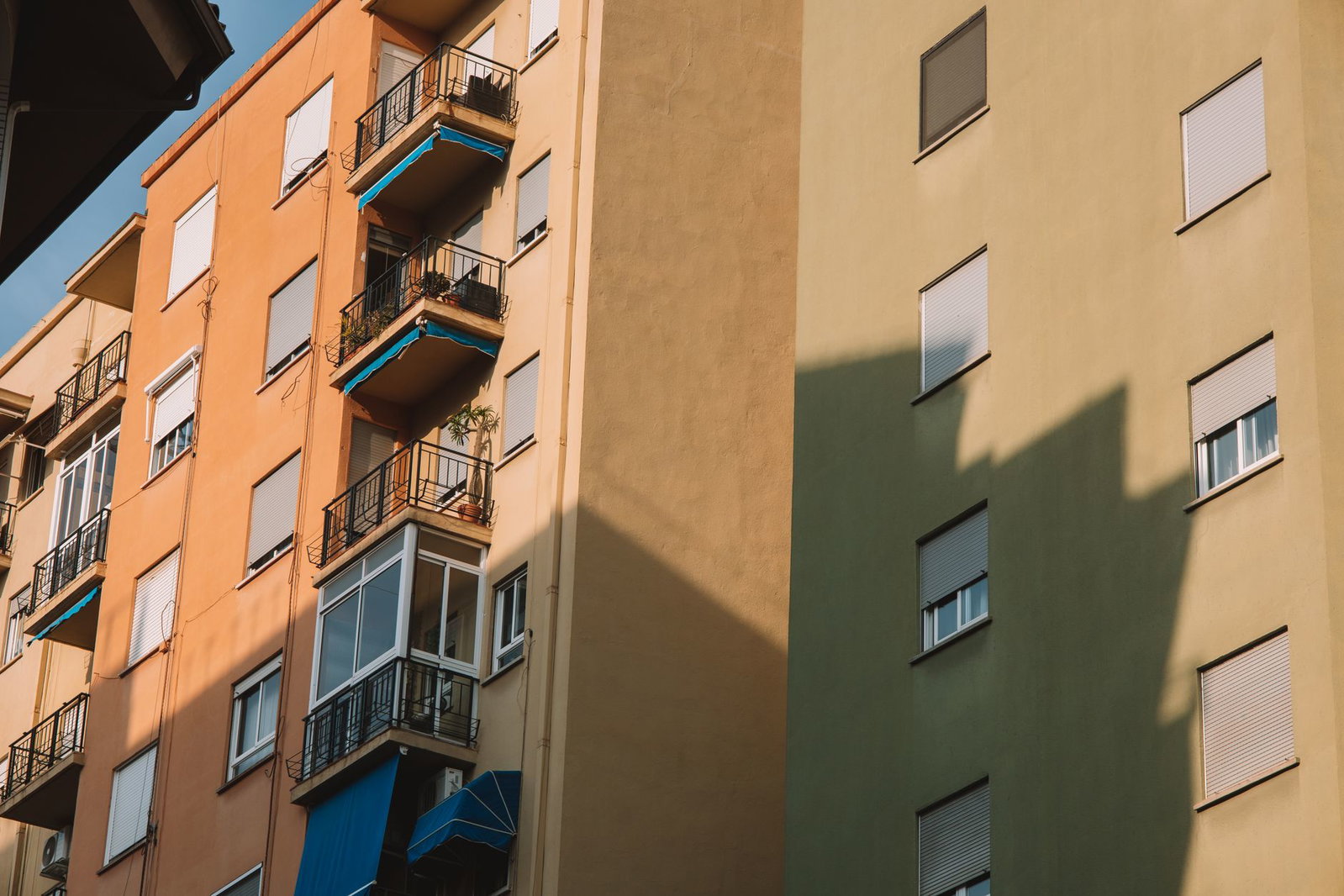 Low angle view of sunlit apartment buildings with balconies in Valencia, Spain.