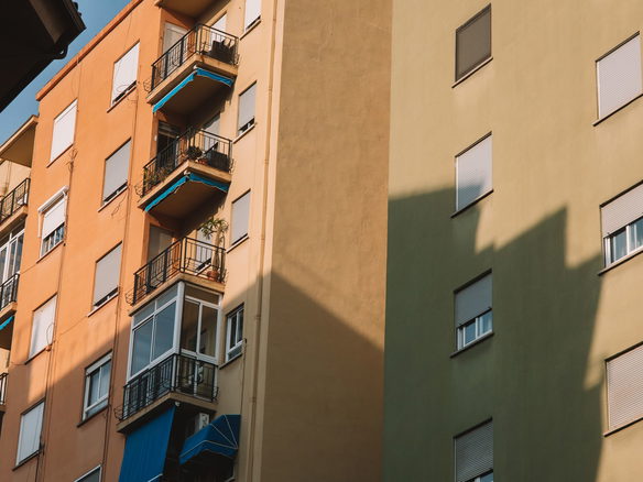 Low angle view of sunlit apartment buildings with balconies in Valencia, Spain.